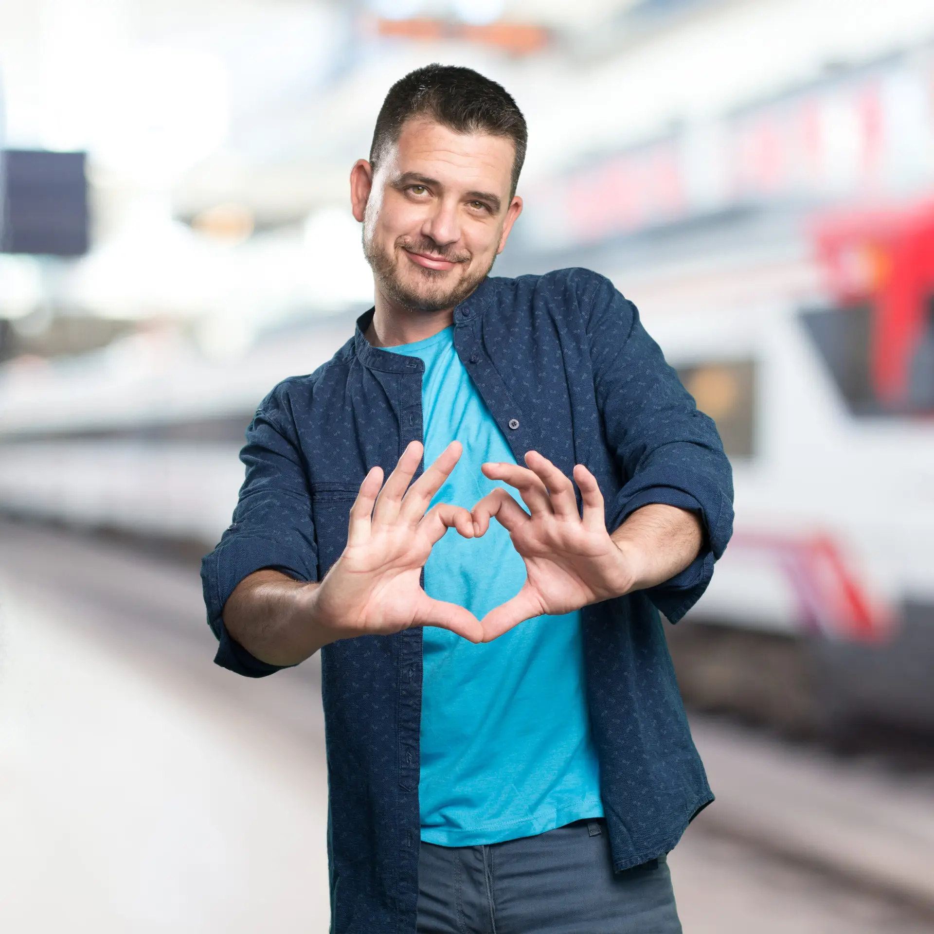 Young man wearing a blue outfit. Doing a heart gesture.
