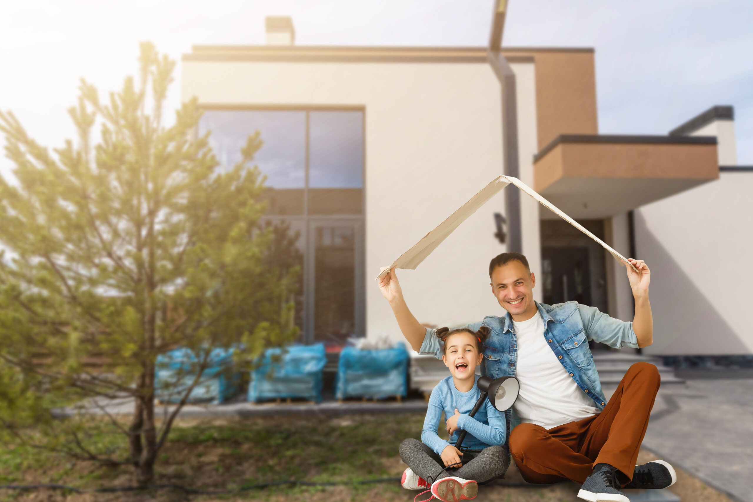 Family sitting on lawn in backyard, big modern house on background.